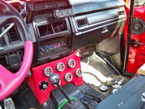 1985 Ford Bronco - The interior of a vehicle shows a custom gauge cluster and a manual transmission shifter.