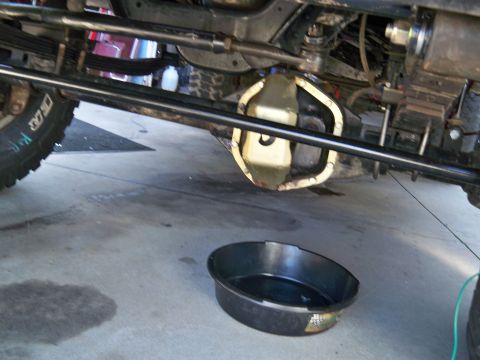 1985 Ford Bronco - Undercarriage view of a vehicle with a drain pan on the concrete floor.