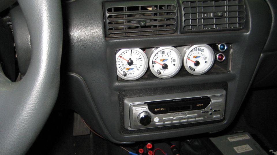 Car dashboard with three gauges and a stereo. One gauge reads boost
