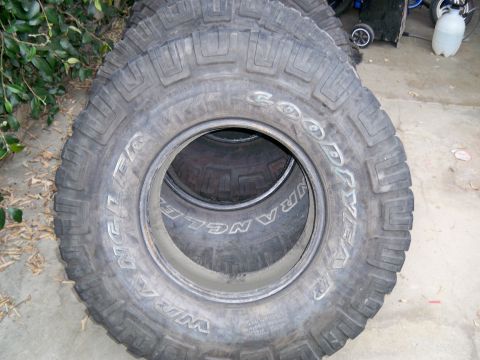 1985 Ford Bronco - Four Goodyear Wrangler tires are stacked, with the front tire showing the brand and model name.
