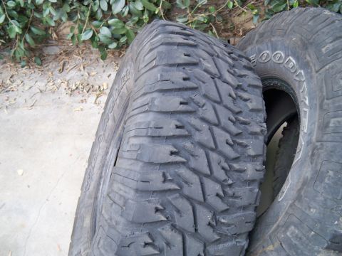 1985 Ford Bronco - A close-up view of two off-road tires, one showing its aggressive tread design.