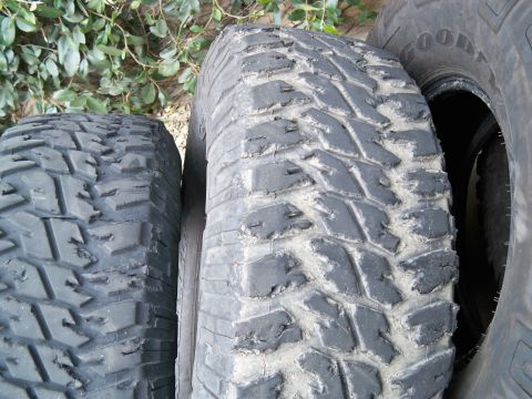 1985 Ford Bronco - Close-up view of multiple off-road tires, some showing wear and dust.