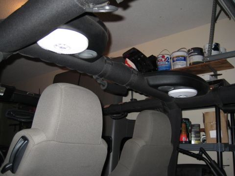 2005 Jeep Wrangler - The interior of a Jeep Wrangler, focusing on the overhead speaker system and seats, in the background, a shelf with paint cans.