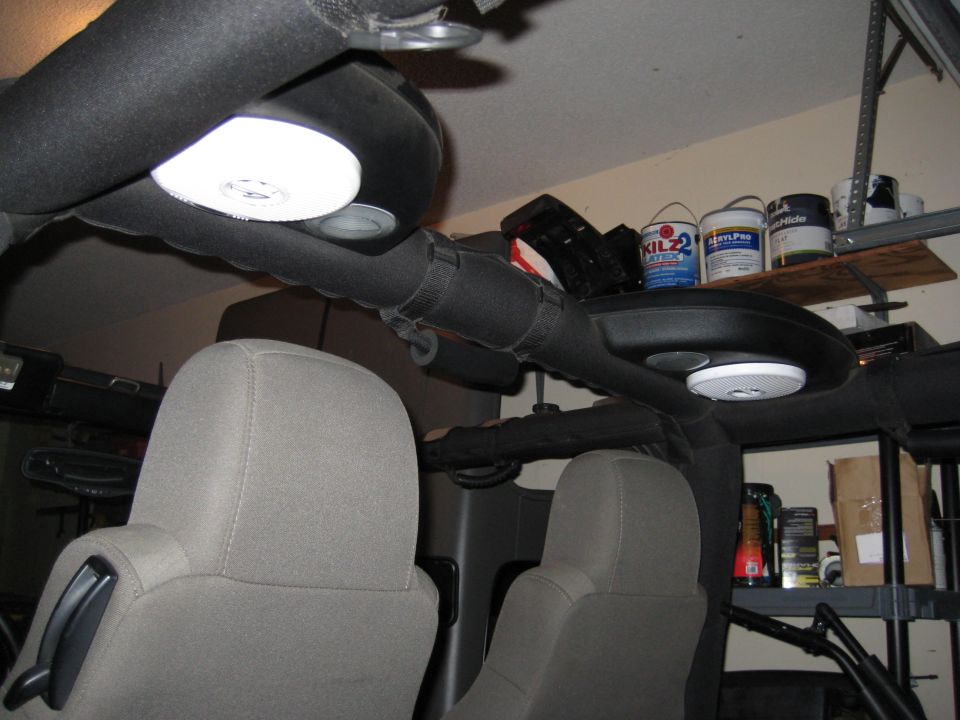 Interior shot of a Jeep Wrangler showing overhead speakers and seats. Paint cans on a shelf in the background