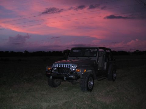 2005 Jeep Wrangler - A Jeep Wrangler sits in a field as the sun sets with a vibrant sky overhead.