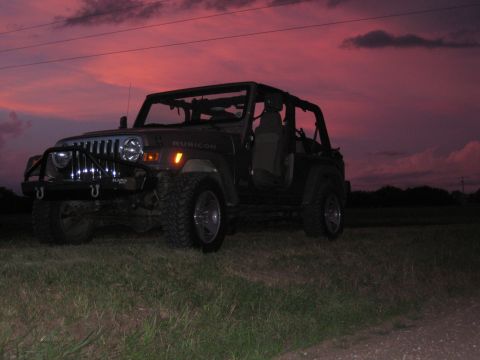 2005 Jeep Wrangler - A 2005 Jeep Wrangler Rubicon is parked in a grassy field under a dramatic sunset sky.