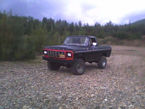 1978 Ford Bronco - A black 1978 Ford Bronco sits on a rocky terrain under a cloudy sky.