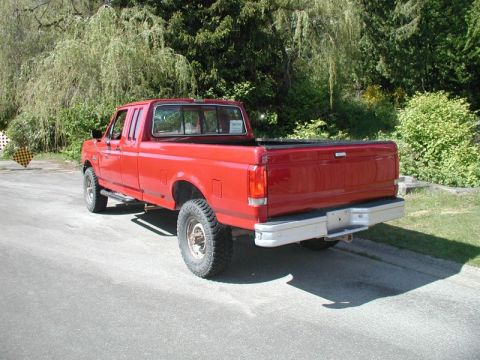 1990 Ford F-250 - This red pickup truck is parked on the side of a road with trees in the background.