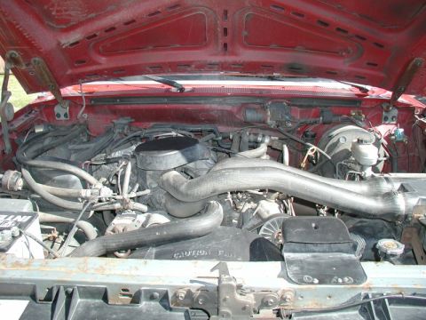 1990 Ford F-250 - The engine bay of a red 1990 Ford F-250 shows a V8 engine with various hoses and components.