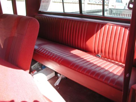 1990 Ford F-250 - The interior of a vehicle features a red bench seat with a seatbelt, and items stored beneath it.