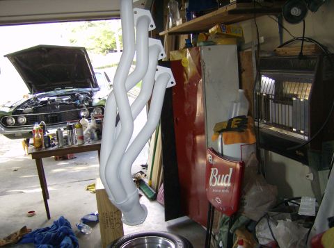 1970 Ford Ranchero - White exhaust headers are displayed in a garage, with a car's engine bay visible on a workbench.