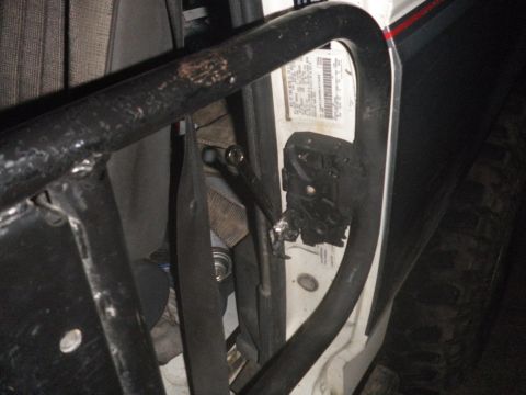 1991 Ford Bronco - Close-up of the interior door frame of a 1991 Ford Bronco, showing a roll cage and latch assembly.