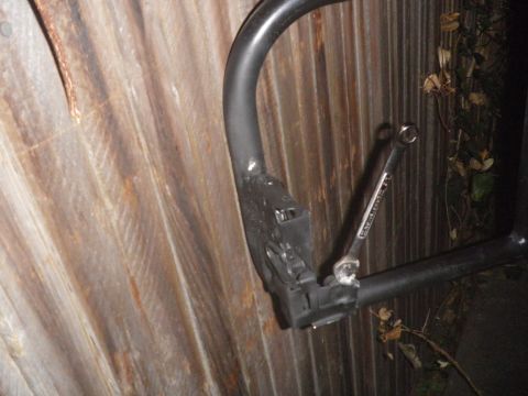 1991 Ford Bronco - A wrench is attached to a metal frame component, with a corrugated wall behind it.