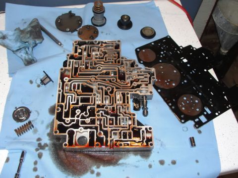 2007 Ford Mustang - Automatic transmission valve body disassembled, showing intricate fluid channels and components.