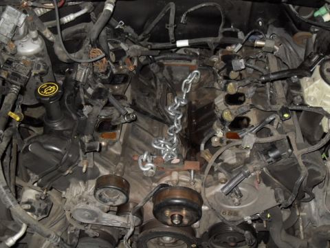 2007 Ford Mustang - The engine bay is shown with a chain suspended over various components and wiring.