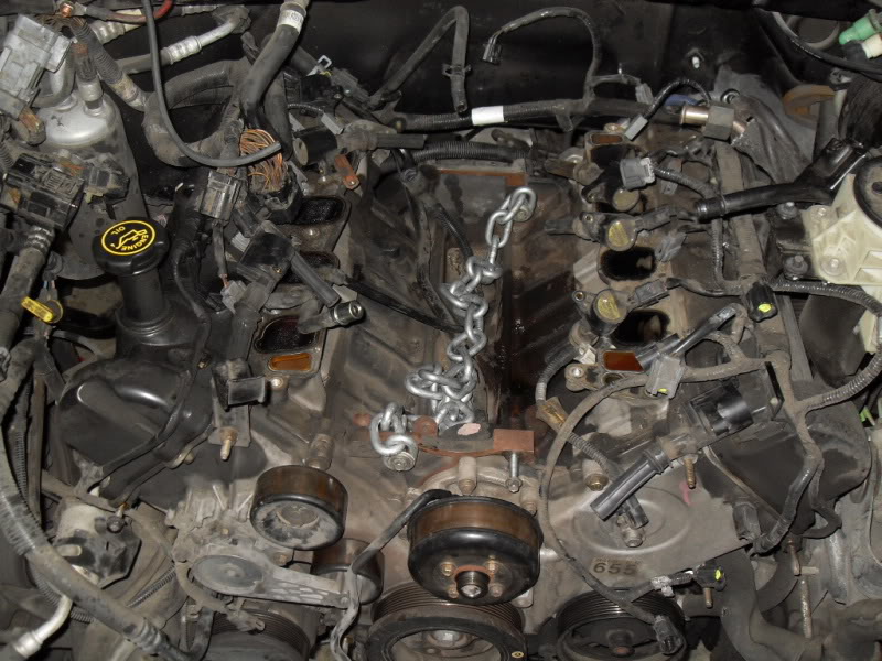 Engine bay with a chain draped over parts. Looks like it's being worked on