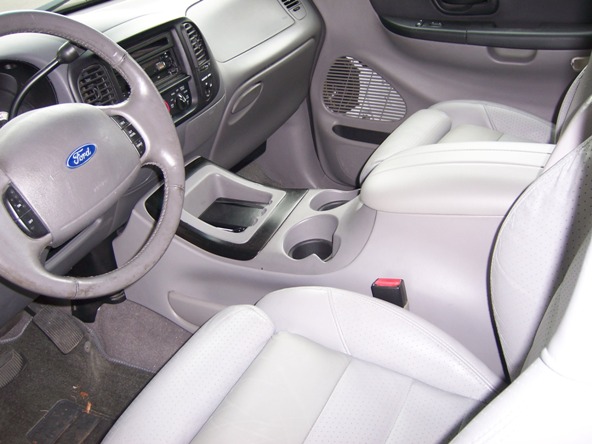 Interior of a light-colored Ford truck, showing the steering wheel, dashboard, and center console