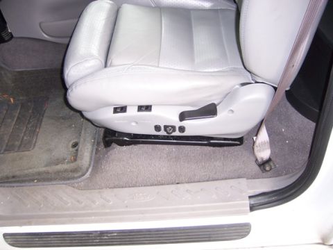 2007 Ford Mustang - The interior of a vehicle shows a light-colored leather seat with visible power adjustment controls and a seatbelt.