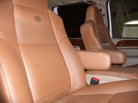 2007 Ford Mustang - Interior view of tan leather captain's chairs wood trim accents and a visible seatbelt.