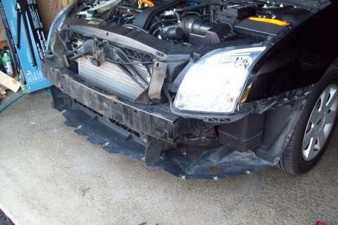 2006 Ford Fusion - Front view of a black car with its bumper detached, revealing the engine and radiator assembly.