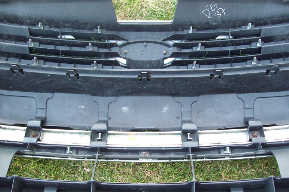 Front grille and bumper section with horizontal slats and chrome trim. White writing on upper black plastic