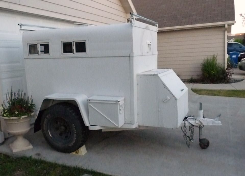 White trailer with two windows on the side, parked on a driveway