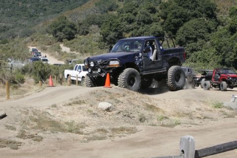 1989 Ford Bronco - A modified 1995 Ford F-150 navigates an off-road course with other vehicles in the background.