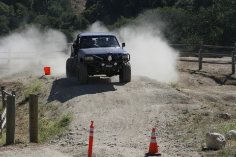 1989 Ford Bronco - An off-road vehicle navigates a dusty dirt track, raising a significant plume of dust.