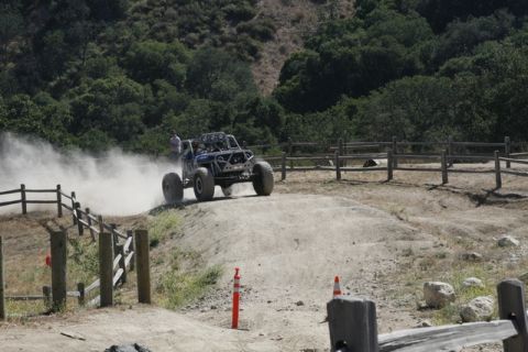 1989 Ford Bronco - Custom off-road buggy navigates a dusty track with trees and fences in the background.