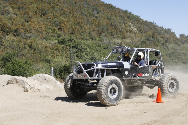 Black off-road buggy with roll cage and large tires driving on dirt