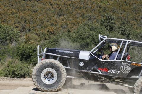 1989 Ford Bronco - Custom off-road buggy navigates a dusty trail with sponsor decals visible on its side.