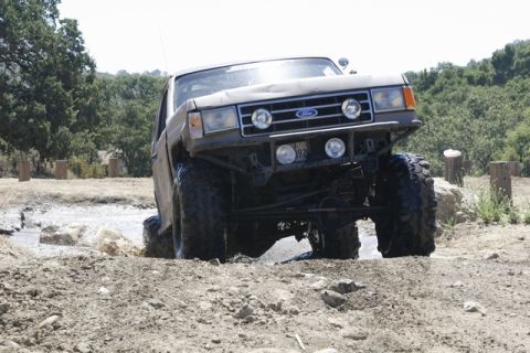 1989 Ford Bronco - This modified Ford Bronco navigates a challenging off-road course, kicking up mud and water.
