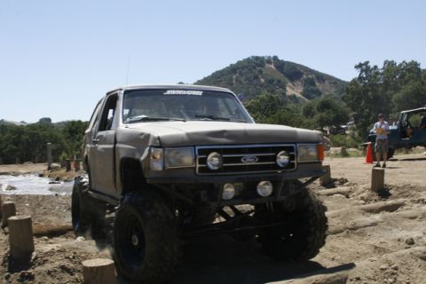 1989 Ford Bronco - A modified Ford Bronco navigates an off-road course with another vehicle visible in the background.