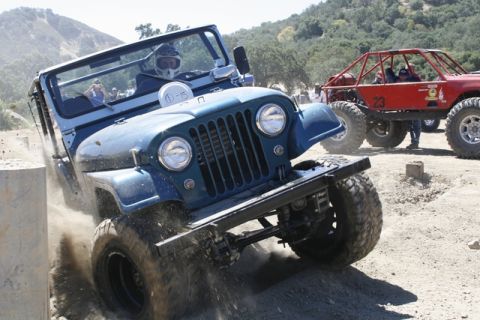 1989 Ford Bronco - Jeep CJ-7 tackles an obstacle course with another off-road vehicle in the background.