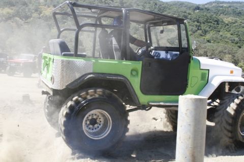 1989 Ford Bronco - An off-road vehicle kicks up dust while driving on a dirt path, with another vehicle visible in the background.