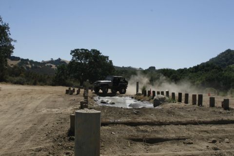 1989 Ford Bronco - A 1989 Ford Bronco navigates a muddy obstacle course, generating a cloud of dust.