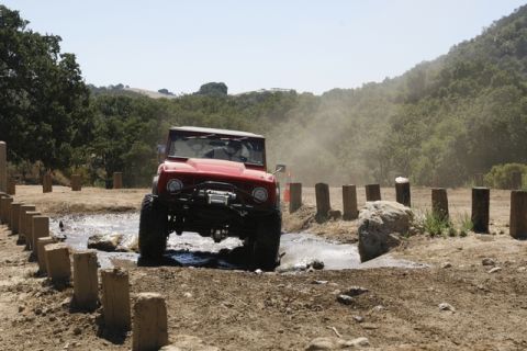 1989 Ford Bronco - A red off-road vehicle navigates a muddy obstacle course.
