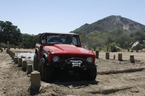 1989 Ford Bronco - This red 1977 Ford Bronco navigates an off-road obstacle course with a prominent winch mounted on the front bumper.