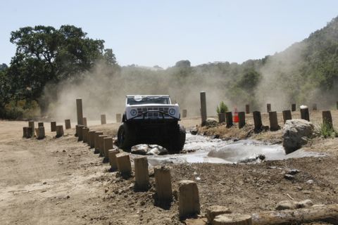 1989 Ford Bronco - This vehicle is navigating a challenging off-road course with mud and obstacles.