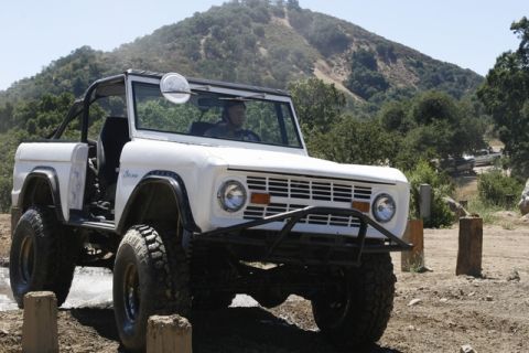 1989 Ford Bronco - This classic white Ford Bronco features off-road tires and a roll cage, suggesting it's built for terrain.