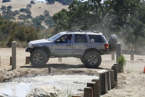 1989 Ford Bronco - This modified Jeep Grand Cherokee navigates a challenging off-road course, kicking up dust and splashing through mud.