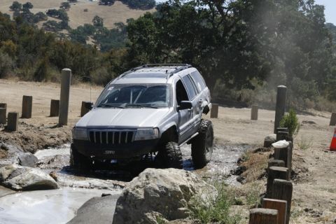 1989 Ford Bronco - A modified Jeep Grand Cherokee tackles a challenging off-road course with water and rocks.