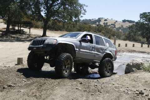 1989 Ford Bronco - A heavily modified Jeep Grand Cherokee navigates an off-road course with large tires and a raised suspension.
