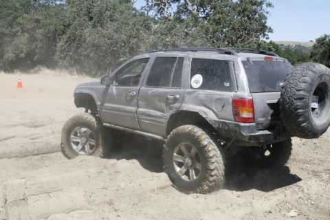 1989 Ford Bronco - This modified Jeep Grand Cherokee is navigating a dirt trail with large off-road tires.