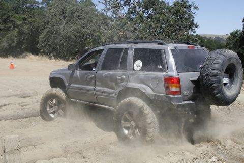 1989 Ford Bronco - A modified Jeep Grand Cherokee navigates a dusty off-road trail.