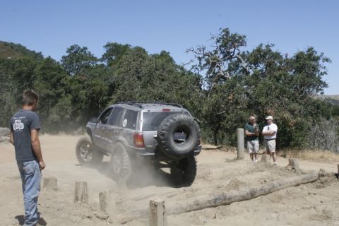 1989 Ford Bronco - A silver SUV navigates an off-road course with a spare tire mounted on its rear.
