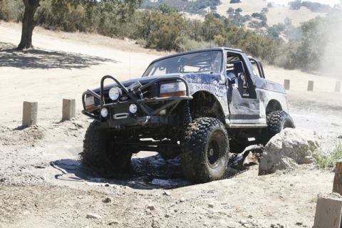 1989 Ford Bronco - This heavily modified 1992 Ford Bronco navigates a challenging off-road course, kicking up mud and water.