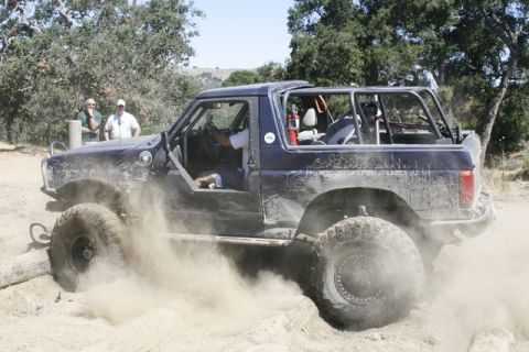 1989 Ford Bronco - This heavily modified SUV is shown navigating a dusty off-road course with a prominent roll cage.