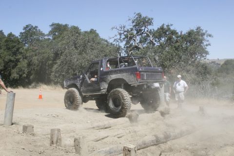 1989 Ford Bronco - A modified 1989 Ford Bronco navigates an off-road obstacle course, kicking up dust.