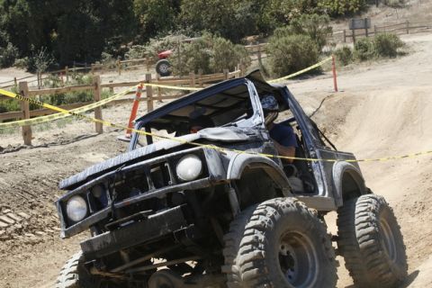 1989 Ford Bronco - An off-road vehicle navigates a challenging dirt track with caution tape marking the course.